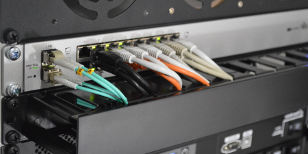 Network cables connected to Ethernet port of a powered switch in server rack.